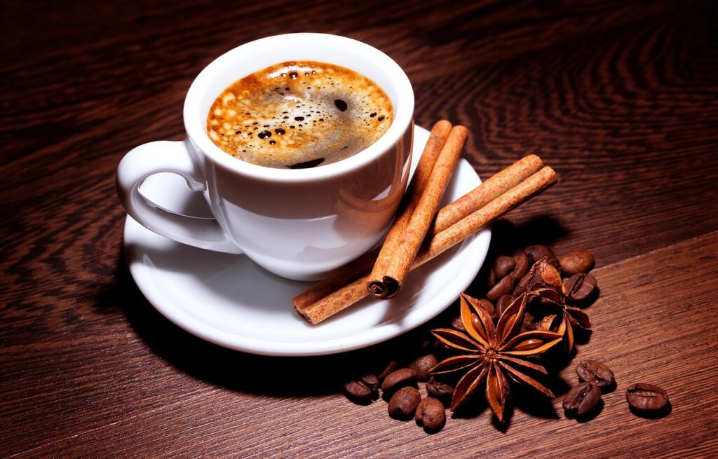 Un expresso accompagné de bâtons de cannelle et de grains de café en fleur 